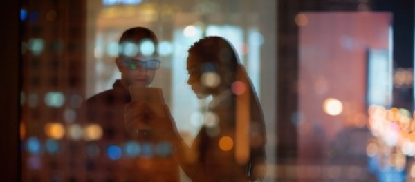 Professionals scanning a dashboard blurred by a foreground of city lights