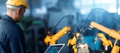 A cybersecurity employee overseeing the OT security of robotic arms in a manufacturing process