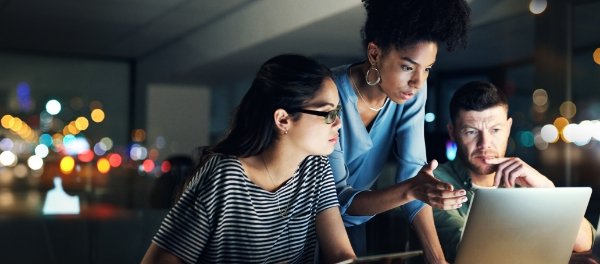 Team concentrating around a computer to drive successful business outcomes